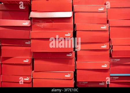 Penang, Malaysia - November 27, 2025: A wall of red Puma shoe boxes is stacked high in a store display, creating a vibrant scene of organized retail p Stock Photo