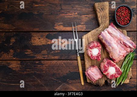 Butcher style raw Lamb oxtail segments with kitchen fork on rustic wooden table, traditional meat for stock and slow cooking. Stock Photo