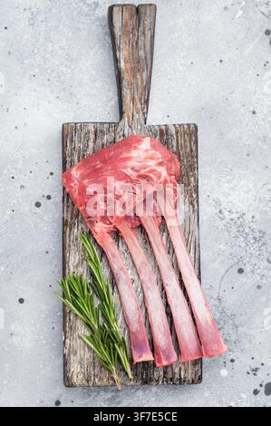 Uncooked lamb ribs and cutlets with herbs and spices on wooden board stone background top view butcher preparation. Stock Photo