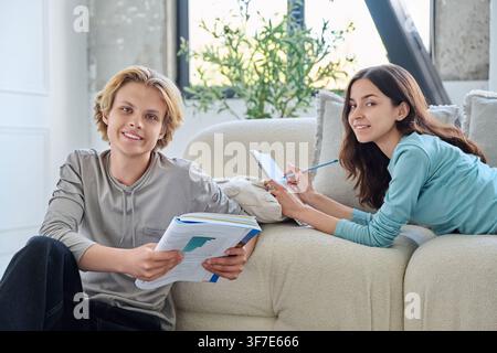 Two smiling young students studying together with books at modern home. Stock Photo