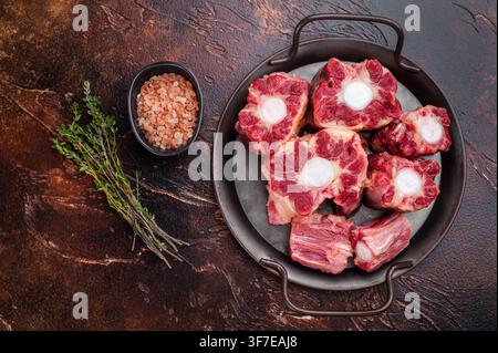 Raw Oxtail pieces in pan with fresh thyme, top view rustic food scene showing collagen rich beef for stock. Stock Photo