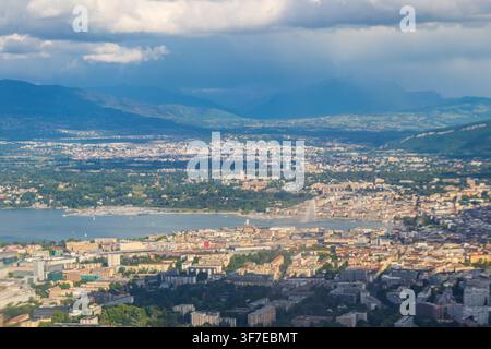 Scenic panoramic cityscape of Geneva with the iconic Jet d'Eau fountain on Lake Geneva under a dramatic sky, Switzerland Stock Photo