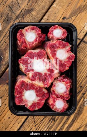 Fresh uncooked mutton lamb oxtail cuts with marrow bones packaged in tray, overhead composition on wooden background Stock Photo