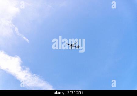Airplane takes off into a blue sky with white clouds, Passenger plane aircraft flying across blue sky background, aircraft gaining altitude, view from Stock Photo