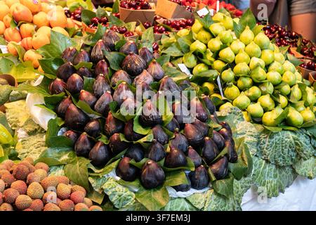 Piles of fresh black and green figs displayed on leaves at the produce stand. Stock Photo