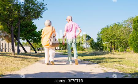 Senior couple walking together on park path enjoying retirement Stock Photo