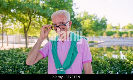 Smiling senior man holding glasses in park Stock Photo