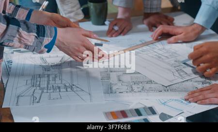 Office casual informal team multiethnic designers drawing blueprint review papers draw building plan analyze work job civil planning electricity build Stock Photo