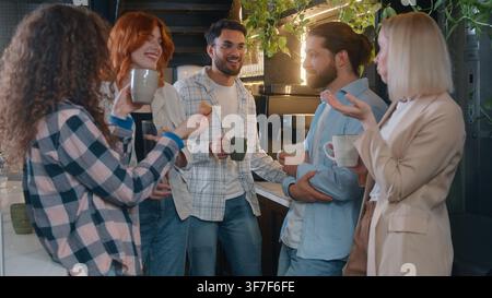 Diversity people men women in cafe office kitchen talking drinking tea pouring coffee in cup laughing casual startup project colleagues friends talk Stock Photo