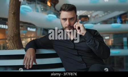 Serious businessman Caucasian man talking mobile phone sitting in business center successful male guy client employer talk smartphone calling client Stock Photo