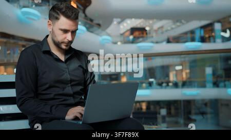 Serious focused Caucasian man businessman worker freelancer working with laptop in business center male guy using computer chatting with client Stock Photo