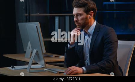 Serious hesitate busy Caucasian business man working with computer think at night office middle-aged businessman male manager work with online Stock Photo
