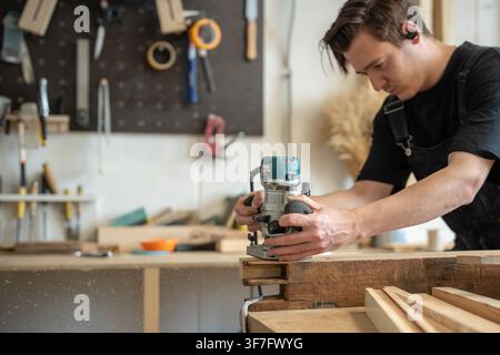 Working process of wooden item renovation in restoration workshop, carpenter using plunge router. Stock Photo