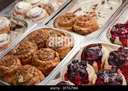 Cinnabons in showcase. Cinamon buns in  Cinnamon rolls with nuts and fruits, isolated. Sweet dessert variaty. Fresh bakery in cafe. Decorated muffins Stock Photo