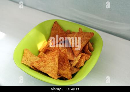 Tortilla chips filling a vibrant green bowl, presenting a classic crunchy snack or appetizer ready for dipping and sharing during casual gatherings Stock Photo