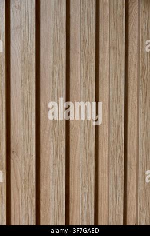 Commercial close-up shot of modern vertical wooden laths with a natural light oak wood grain texture. This wall cladding element is widely used in contemporary architectural projects for interior decoration, providing a clean, minimalist, and textured aesthetic for residential or office spaces. Stock Photo