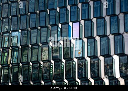 Abstract geometric texture of the three-dimensional hexagonal glass panels of Harpa Concert Hall in Reykjavík, Iceland, featuring daylight reflections Stock Photo