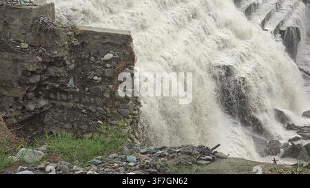 Water rushing over stone retaining wall with a low angle view of water spilling Stock Photo