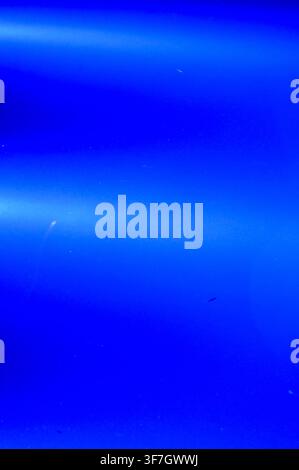 Commercial close-up of deep marine water illuminated by a yacht's underwater lights, creating glowing blue horizontal bands. Stock Photo