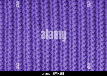 Close up, macro of purple knitted fabric texture with visible yarn stitches and soft wool pattern. Cozy textile backdrop, cloth background, fashion wa Stock Photo