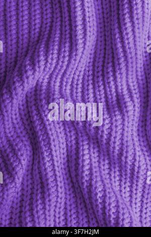 Close up, macro of crumpled purple colored knitted fabric. Cloth with visible wrinkles, folds and soft waves. Soft wool material texture with detailed Stock Photo