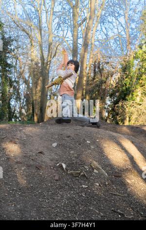 A boy enjoys playtime on a rope tree swing in the woods at London’s Hampstead Heath, a landmark renowned for outdoor adventure. Stock Photo
