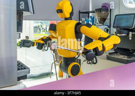 Humanoid robot prepares coffee using automatic coffee machine in Shenzhen, China. Artificial intelligence, robotics, service automation, smart Stock Photo