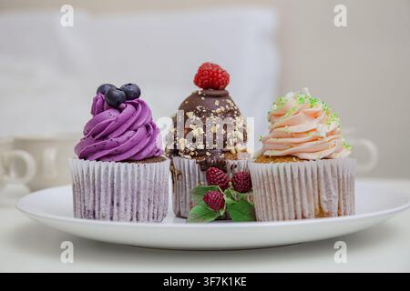 Colorful cupcakes stand, display and present swirled frosting and fresh berries on a white plate, sweet dessert, celebration food. Stock Photo