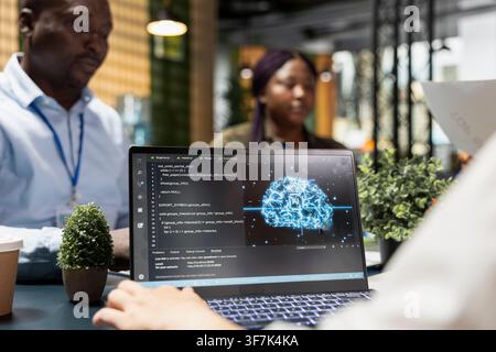 AI company programmers doing brainstorming to create deep learning models with laptop. IT employees cooperating on artificial intelligence project to develop solutions for businesses Stock Photo