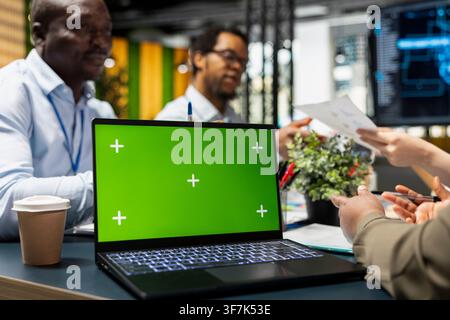 Green screen laptop used by programmers developing software, designing coding solutions together. Coworkers analyze technical issues with mockup notebook, optimizing performance, closeup Stock Photo