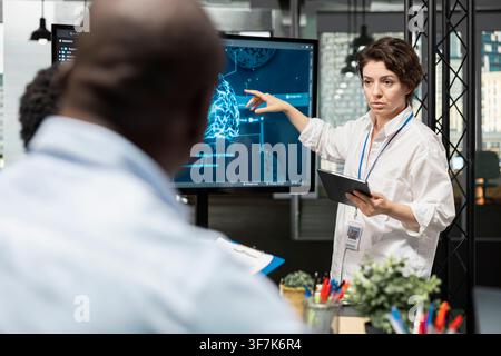 Startup IT employees discussing deep learning tech roadmap during briefing session. Technicians developing neural network applications in office, analyzing system performance metrics after QA testing Stock Photo