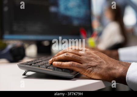 Close up of engineer typing on keyboard in office, using AI on computer to streamline app development. Worker writing code at desk using PC to run debugging programs with machine learning technology Stock Photo