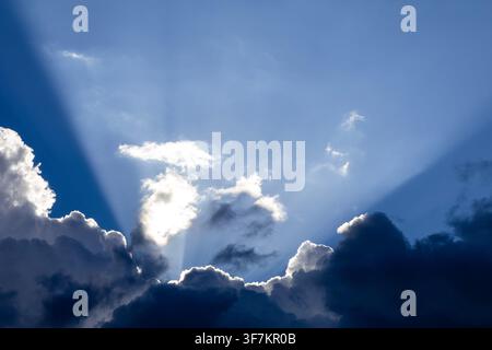 Dramatic God crepuscular rays streaming through dense dark storm clouds Stock Photo