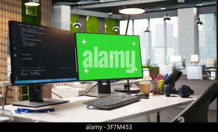 Empty startup office with green screen PC and artificial intelligence program running on monitors. Mockup computer display in AI industry startup workspace leveraging machine learning technology Stock Photo