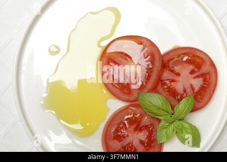 Sliced tomatoes on plate with olive oil Stock Photo