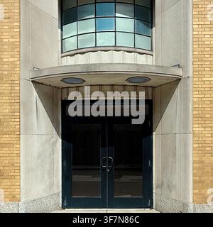Streamline Moderne entrance doors beneath a projecting canopy and curved window on an urban Chicago building facade. Stock Photo