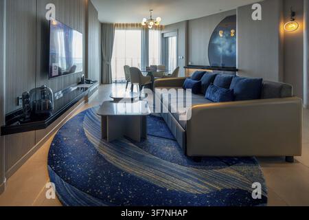 Hotel suite living area with sofa, dining table and XXL television, Pattaya, Thailand Stock Photo