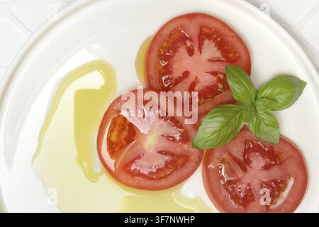 Sliced tomatoes on plate with olive oil Stock Photo