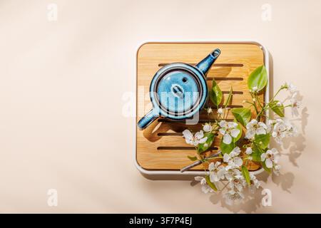 Blue ceramic teapot with blooming spring branch on wooden tray in minimal asian style composition Stock Photo