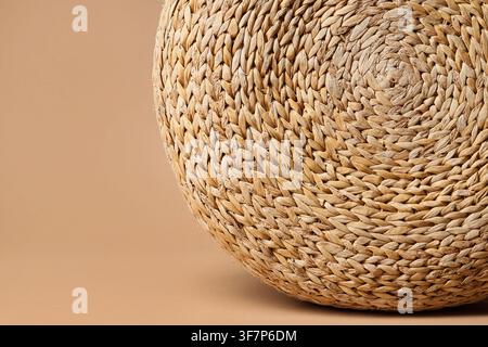 Woven natural fiber pouf with intricate texture and circular pattern on a neutral background, home decor and craftsmanship Stock Photo