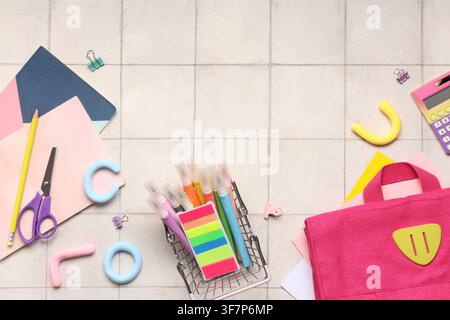 Colorful school supplies and stationery items arranged on a light tiled background with copy space for educational themes Stock Photo