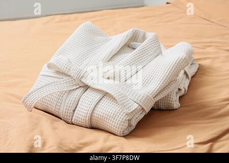 Folded waffle bathrobes on bed in room Stock Photo