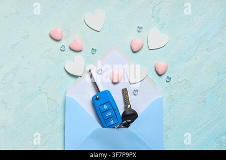 Envelope with car keys and hearts on light grunge background Stock Photo