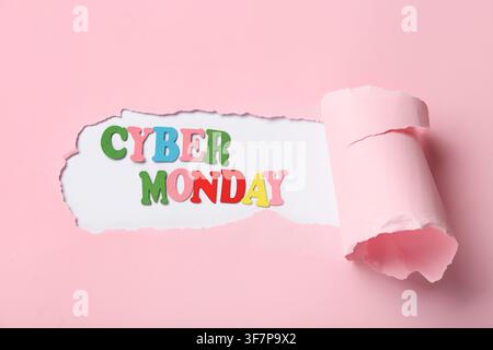 Text CYBER MONDAY visible through hole in torn pink paper on white background Stock Photo