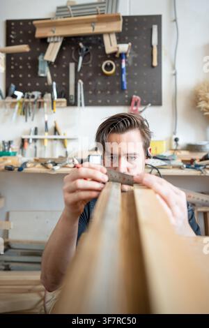 Man woodworker precisely measuring wooden board patch replacement for antique window frame. Stock Photo