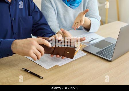 Senior couple checking empty wallet while budgeting and paying bills at home Stock Photo
