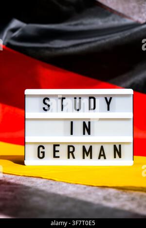 Lightbox with text STUDY IN GERMAN National symbol of Germany. German wave silky flag background. Concept of education and learning  Stock Photo