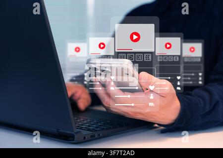 Man using smartphone and laptop with a virtual video player interface, symbolizing streaming media, mobile apps, online entertainment, content access, Stock Photo