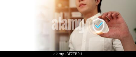 Man holding virtual shield icon with checkmark for security and protection Stock Photo