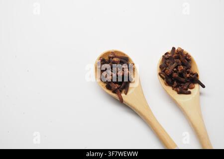 Cloves in wooden spoons on a white background Stock Photo